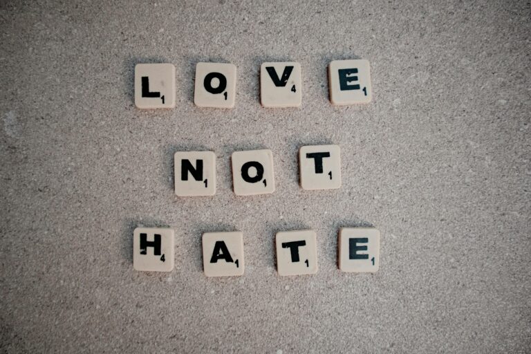 Scrabble tiles on pavement spelling the inspirational message 'Love Not Hate'.