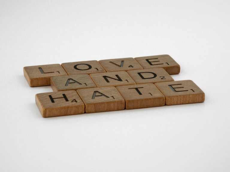 Close-up of Scrabble tiles spelling 'Love and Hate' on a white background, symbolizing complex emotions.